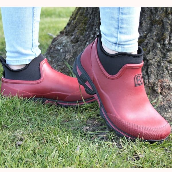 Korte røde gummistøvler med neopren på et par fødder.